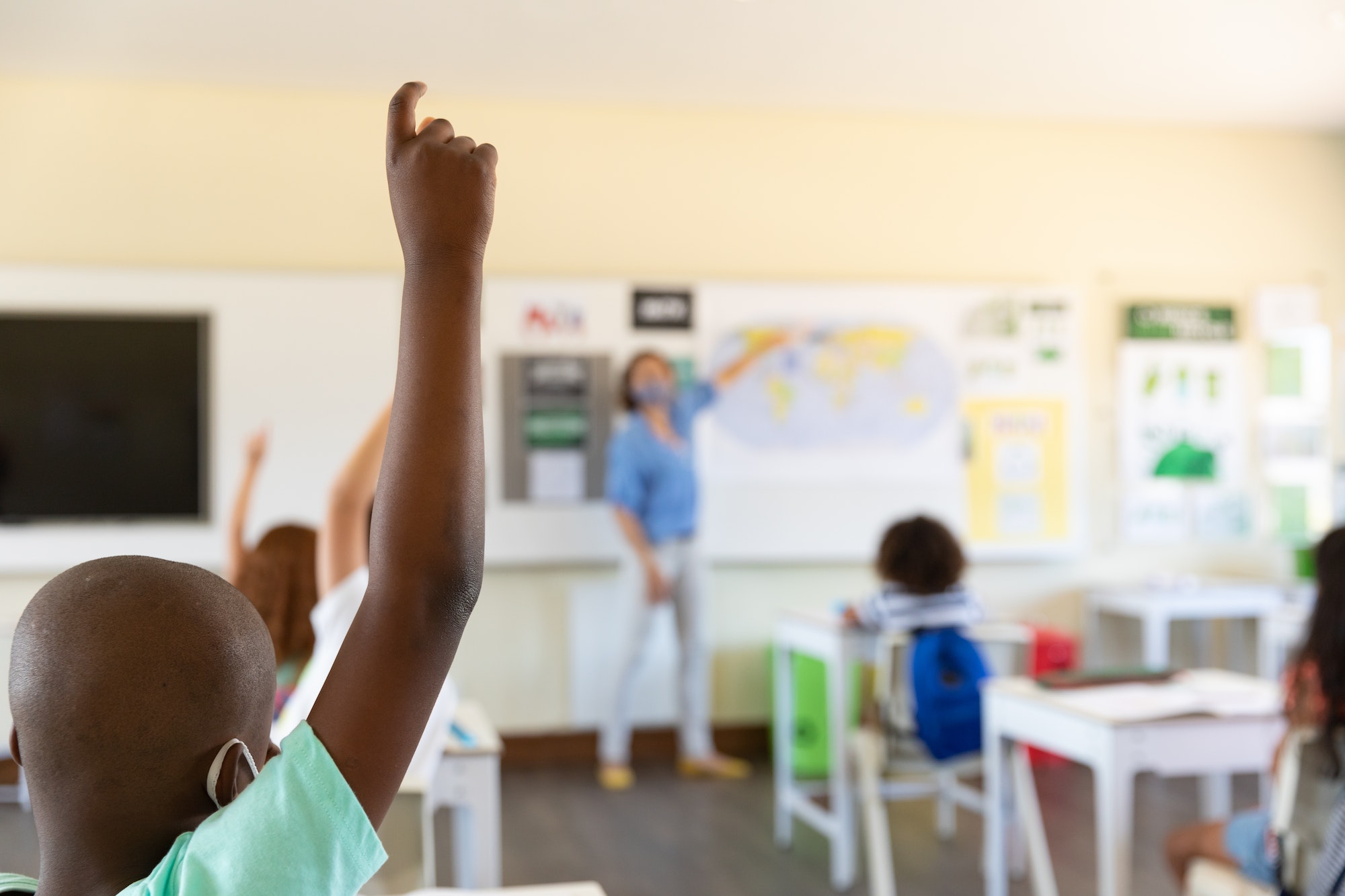 Students raising hands in class at school